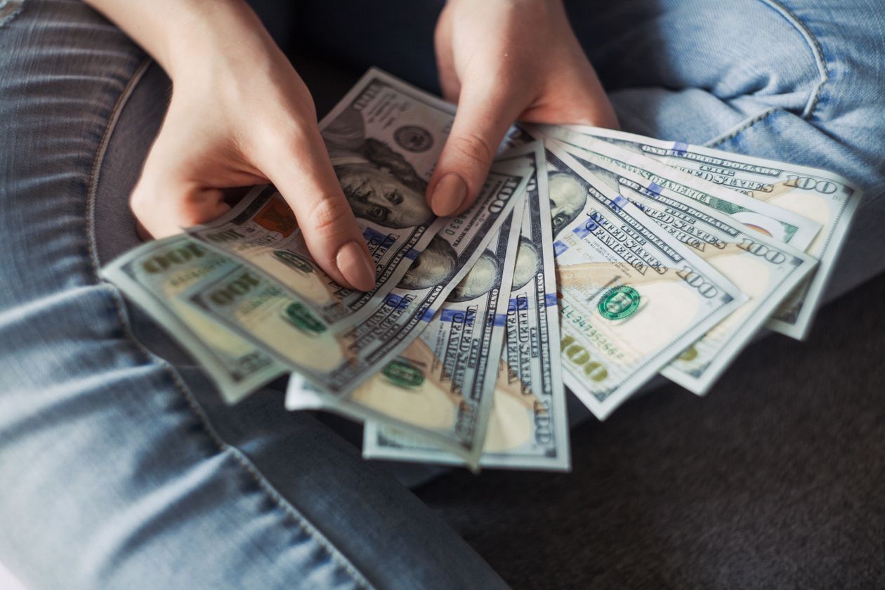 Manos sosteniendo billetes de dólar en abanico