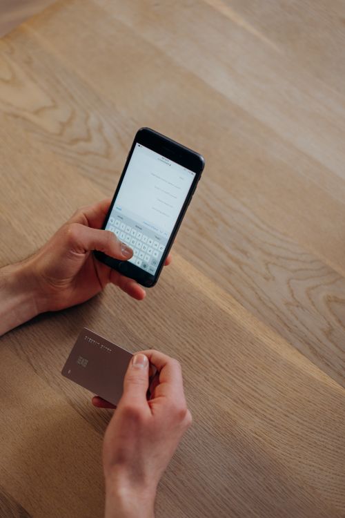 Mano sosteniendo un teléfono con la app del banco y una tarjeta de débito