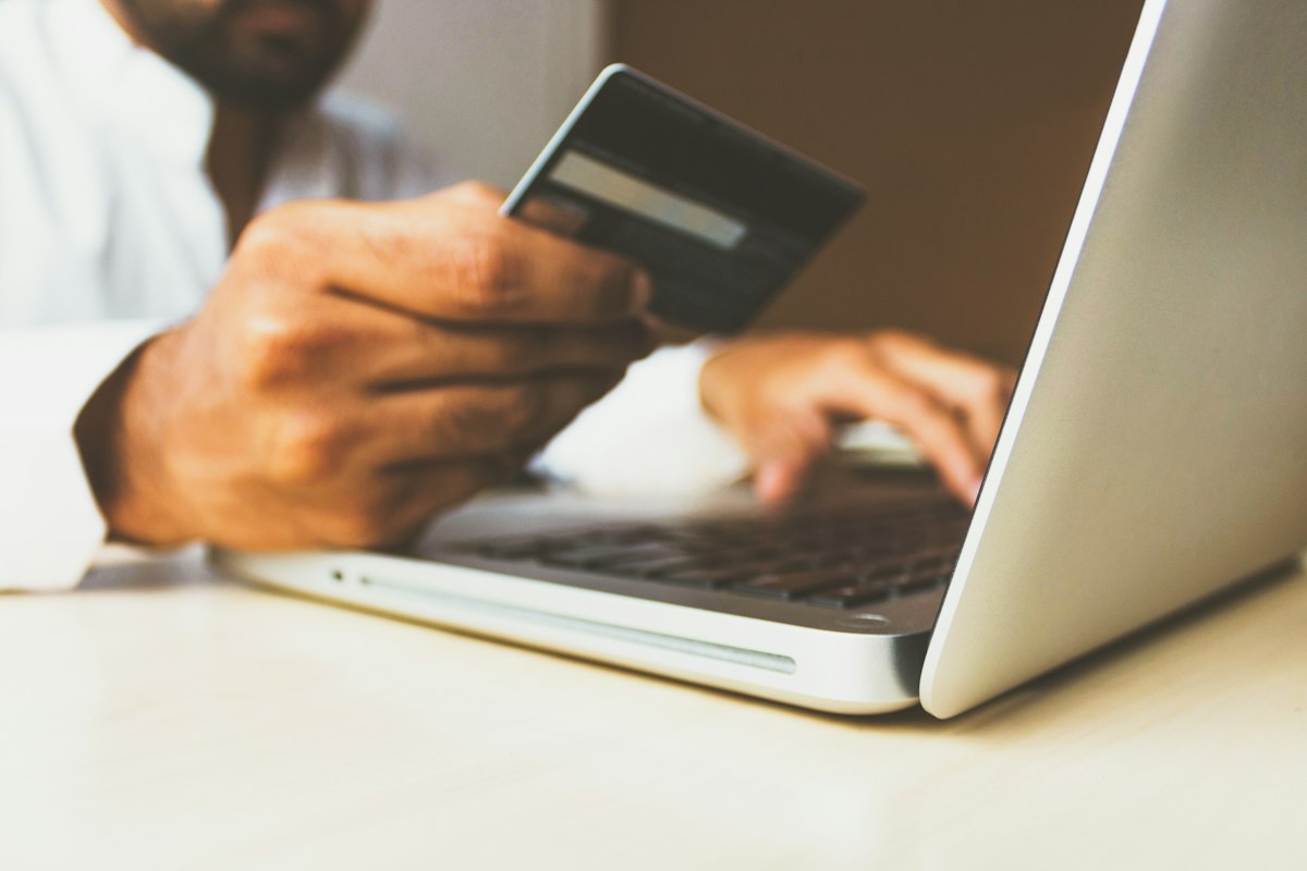 Mano con tarjeta comprando en laptop